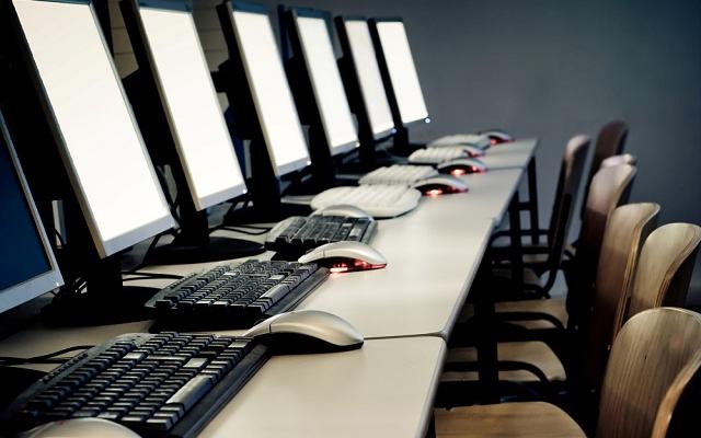 picture of many computers with empty chair in front of them